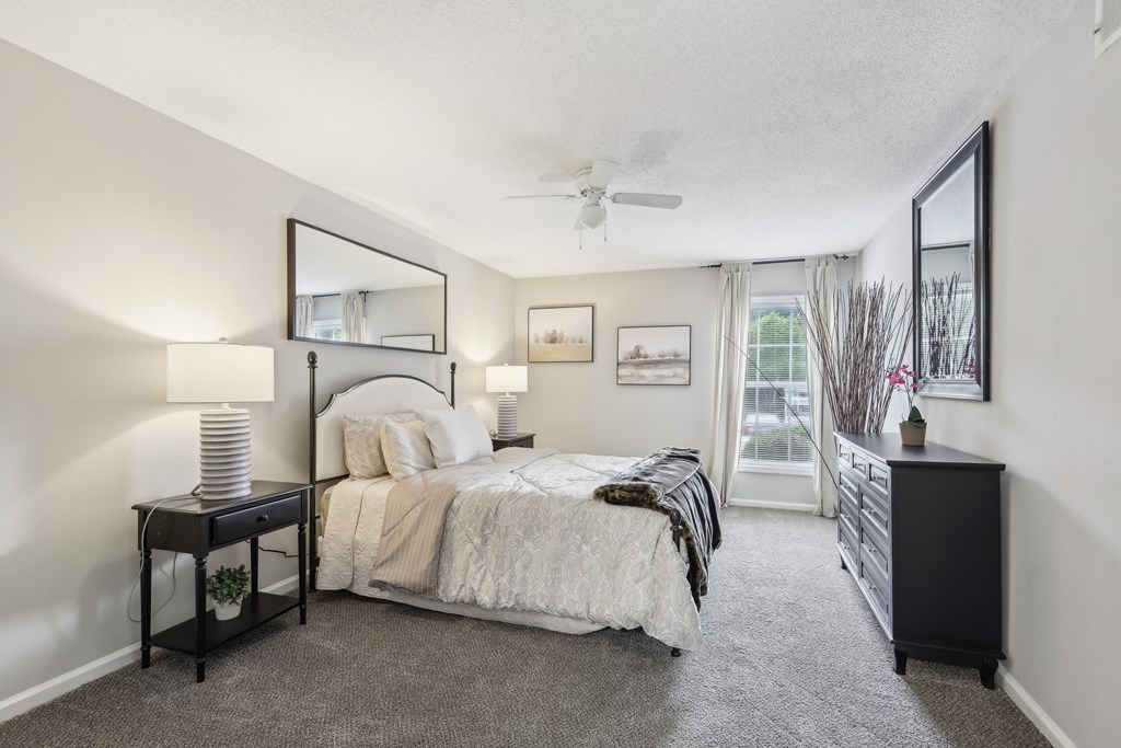 A bedroom with a bed, nightstand, and a window with a view.