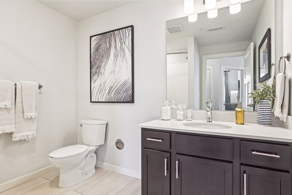 A bathroom with a toilet, sink, and mirror. at Connect at First Creek Apartments, Colorado