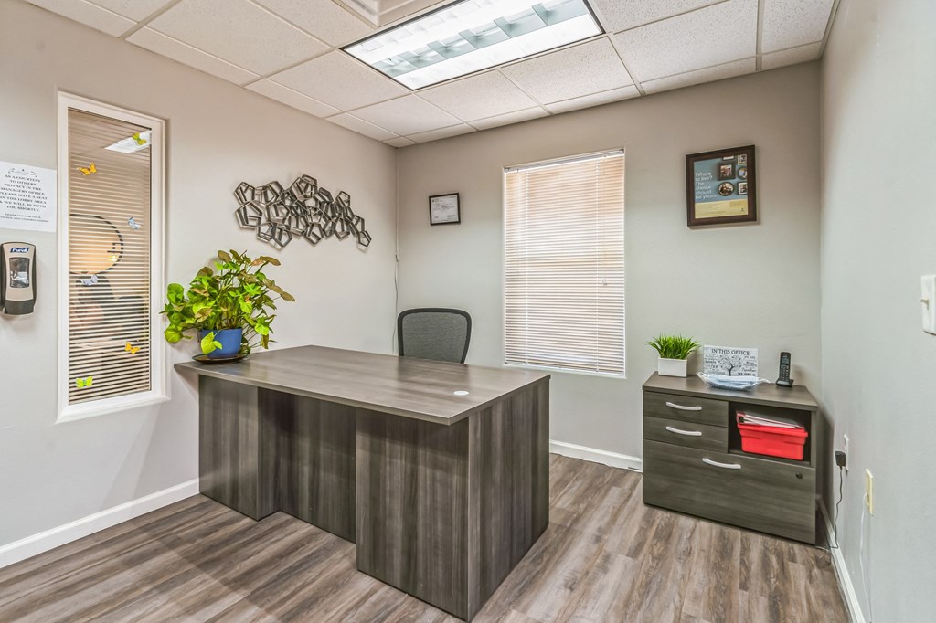 A grey reception desk with a plant on it and a framed picture on the wall.