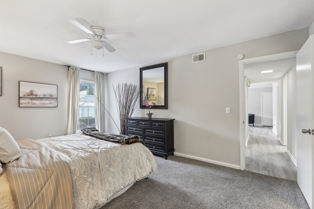 A bedroom with a bed, dresser, and a painting on the wall.
