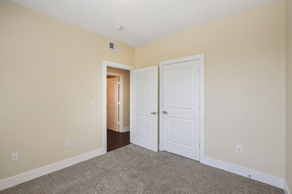 A room with a carpeted floor and two white doors. at Province of Briarcliff Apartments, Kansas City, 64118