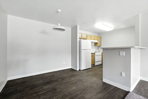 A kitchen area with white cabinets and a wooden floor.