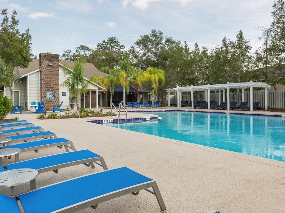 a large swimming pool with blue lounge chairs