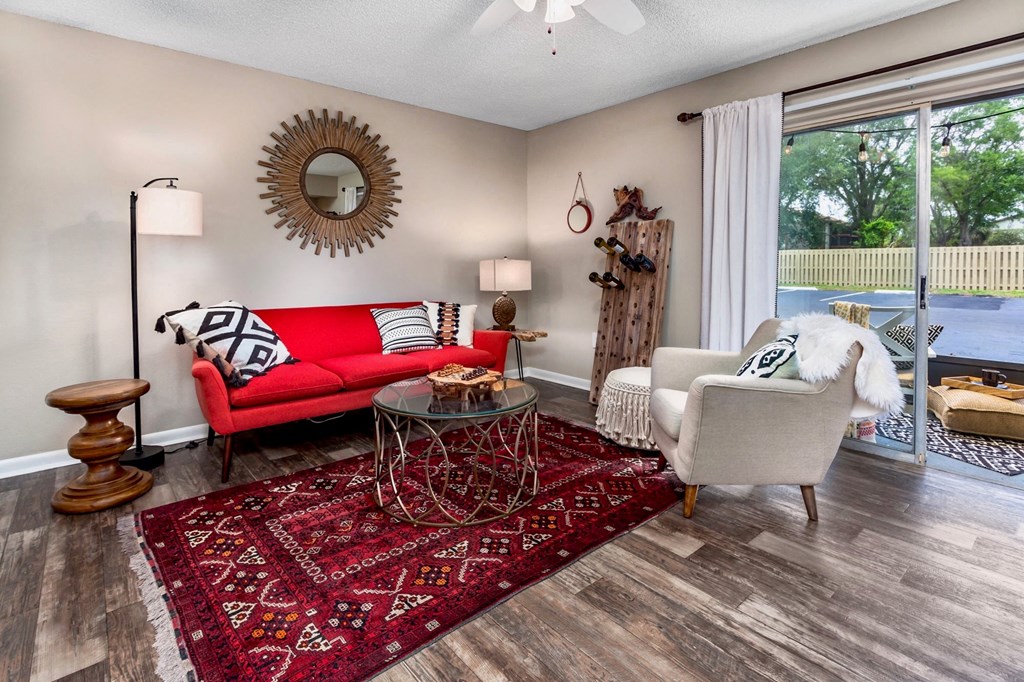 a living room with a red couch and chairs and a large window