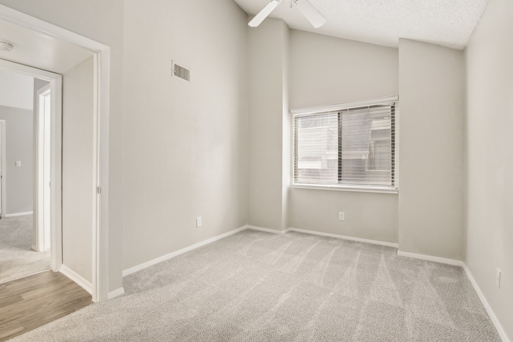 A room with a carpeted floor and a window with blinds.