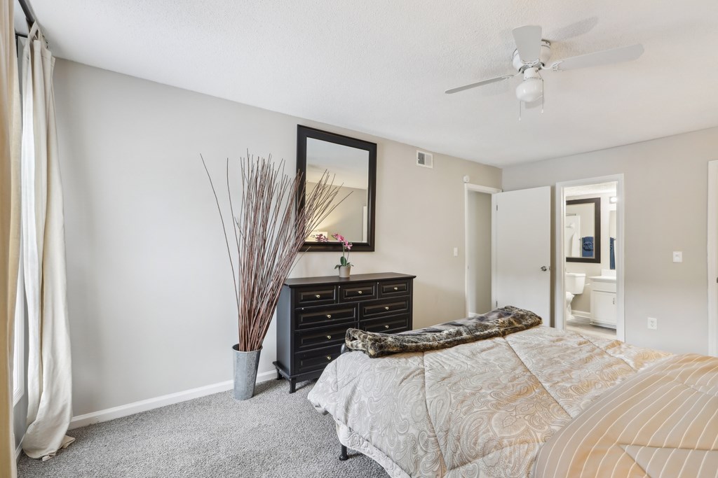 A bedroom with a bed, dresser, and mirror.