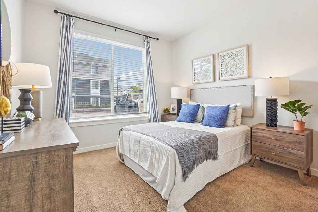 A bedroom with a large bed and a window with blinds. at Connect at First Creek Apartments, Colorado, 80249