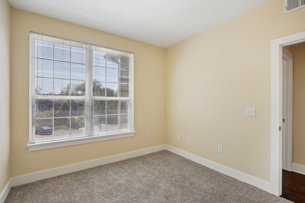 A room with a window and a car parked outside. at Province of Briarcliff Apartments, Kansas City, 64118