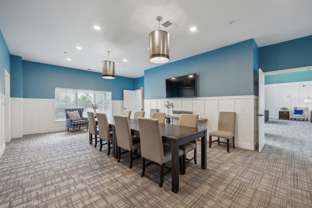 a dining room with a table and chairs and a tv at The Hendrickson, Falcon Heights