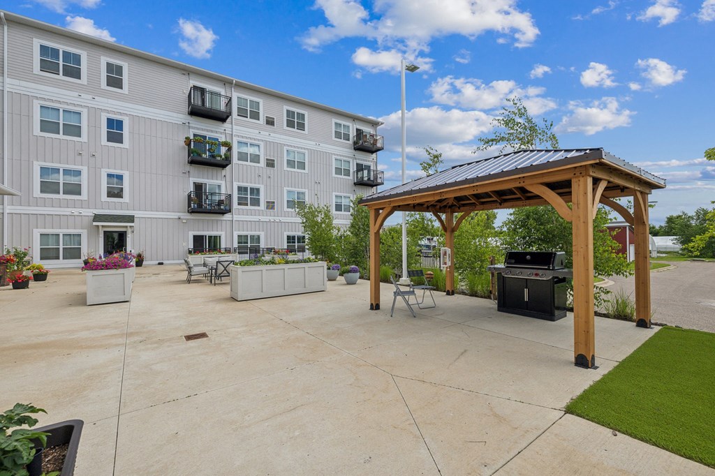 An Outdoor Patio With Gazebo For senior 55+ Community Living By Hendrickson Apartments in MN an outdoor patio with a gazebo and an apartment building at The Hendrickson, Falcon Heights, MN, 55113