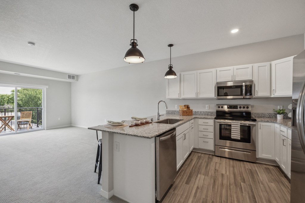 an open kitchen with stainless steel appliances and white cabinetry at The Hendrickson, Falcon Heights, MN, 55113