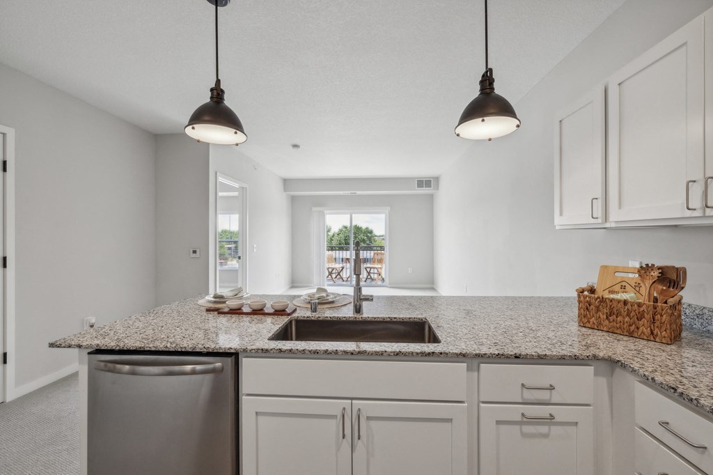 A well-maintained kitchen with Cabinets for senior 55+ Community Living By Hendrickson Apartments a kitchen with white cabinets and granite counter tops and a sink at The Hendrickson, Minnesota