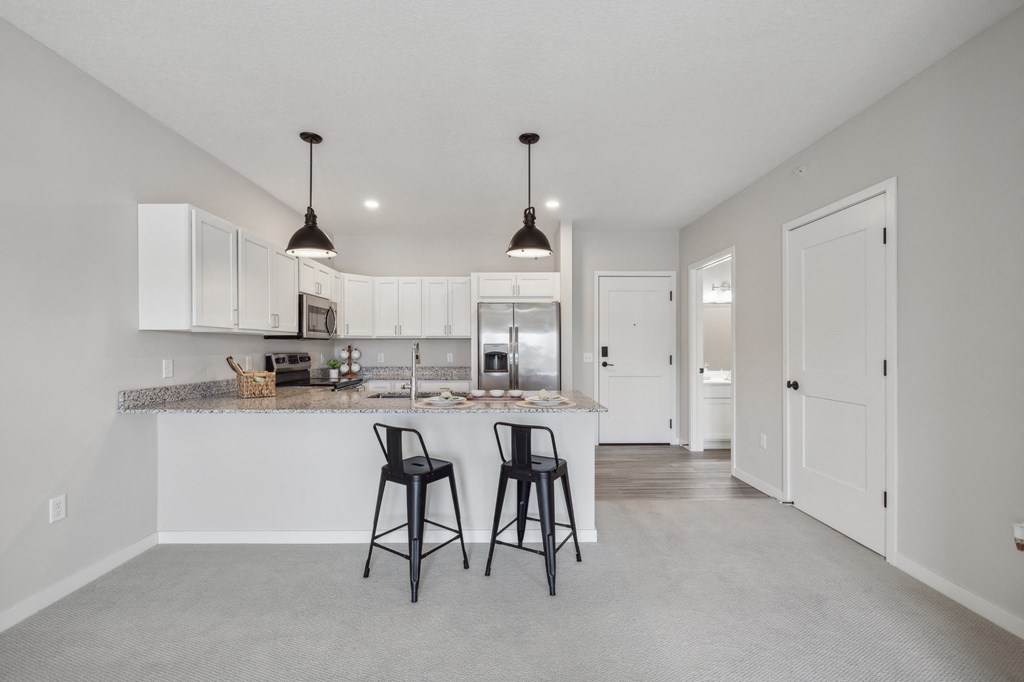 the living room and kitchen in a new home with white cabinets at The Hendrickson, Falcon Heights