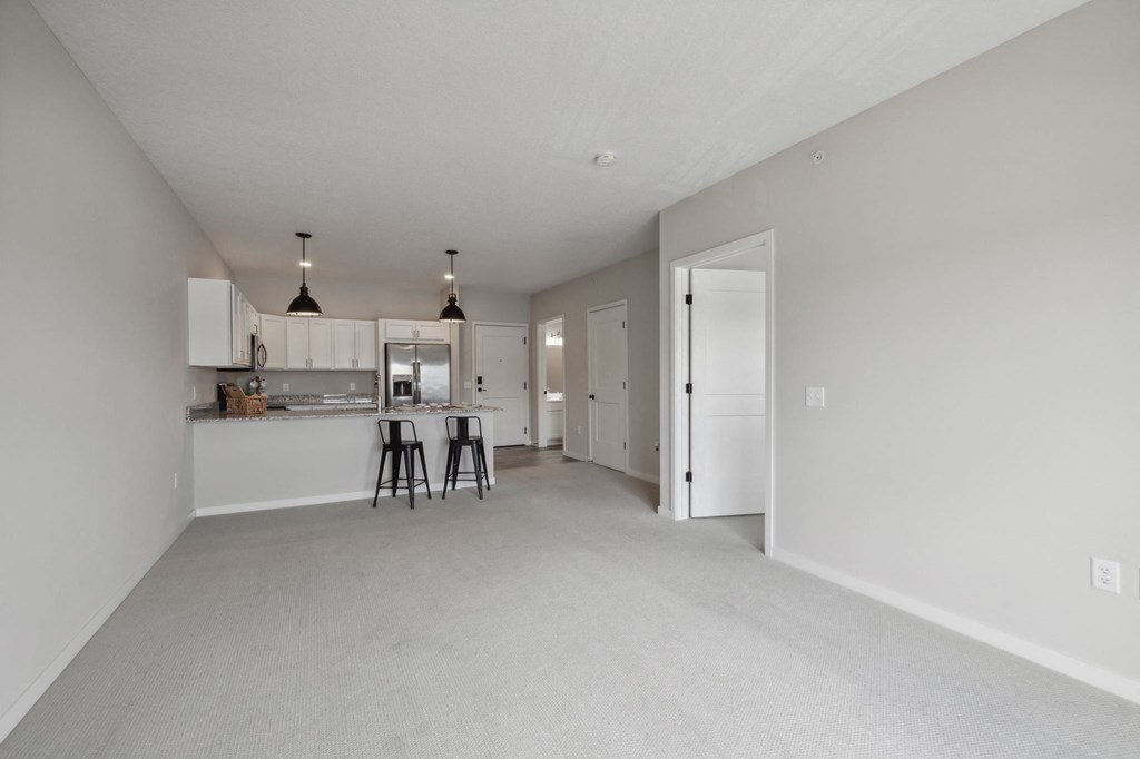 the living room and kitchen of an apartment with white cabinets and a white kitchen counter at The Hendrickson, Falcon Heights, MN, 55113