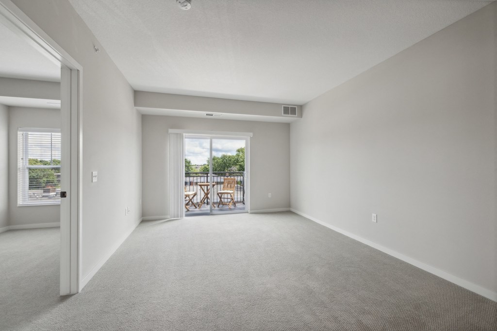 an empty living room with a door to a balcony at The Hendrickson, Falcon Heights, MN