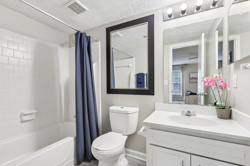 A white bathroom with a toilet, sink, and mirror.
