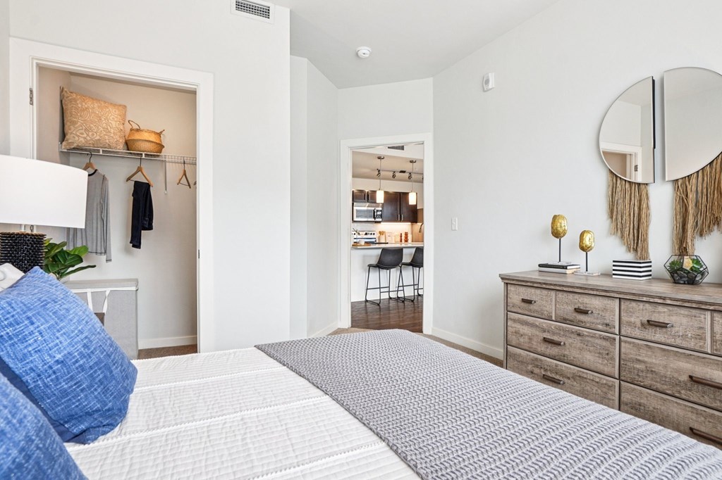 A bedroom with a large bed and a mirror on the wall. at Connect at First Creek Apartments, Denver, CO
