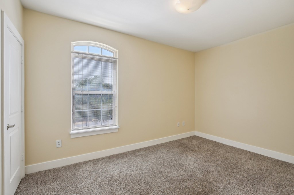 A room with a carpeted floor and a window with blinds. at Province of Briarcliff Apartments, Kansas City, Missouri