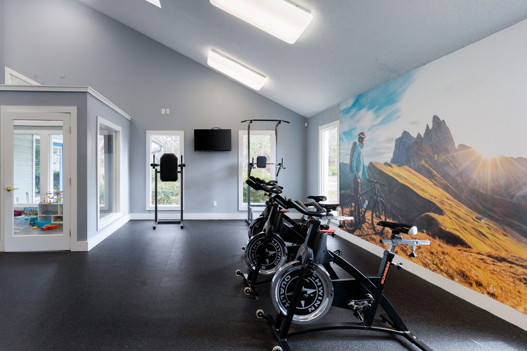 A room with a wall mural of a mountainous landscape and two bicycles leaning against a stand.