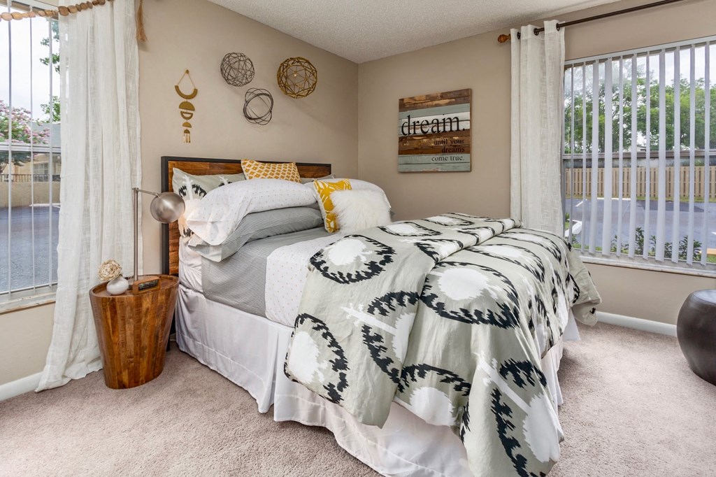 a bedroom with a bed and windows with curtains