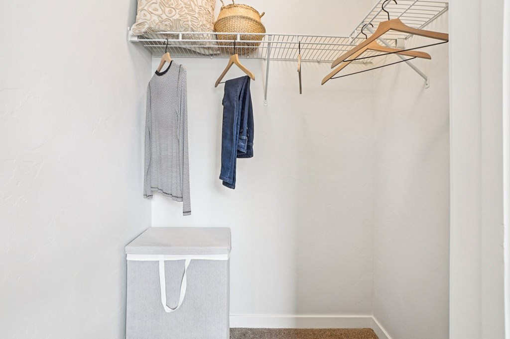 A white closet with clothes hanging and a basket on the shelf. at Connect at First Creek Apartments, Denver, Colorado