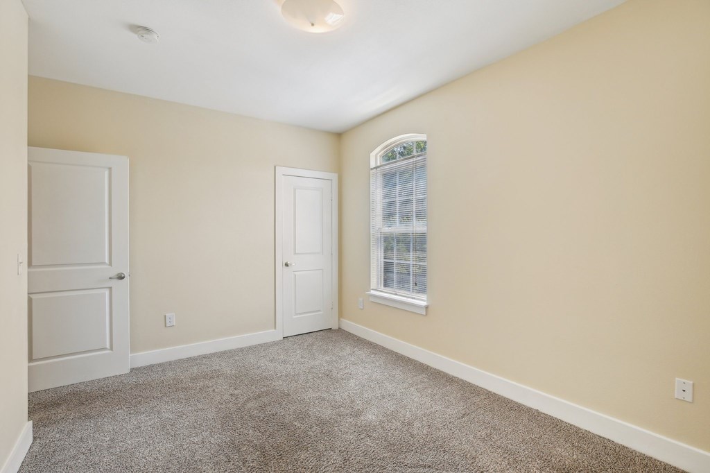 A room with a carpeted floor, two doors, and a window with blinds. at Province of Briarcliff Apartments, Missouri