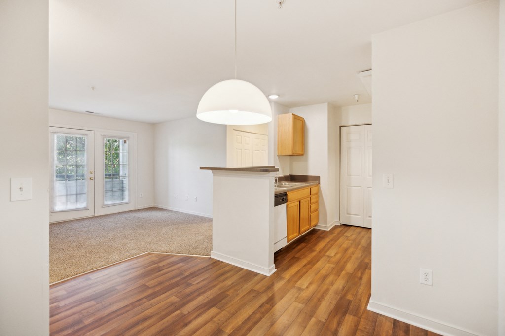 an empty living room and kitchen with wood flooring and a window
