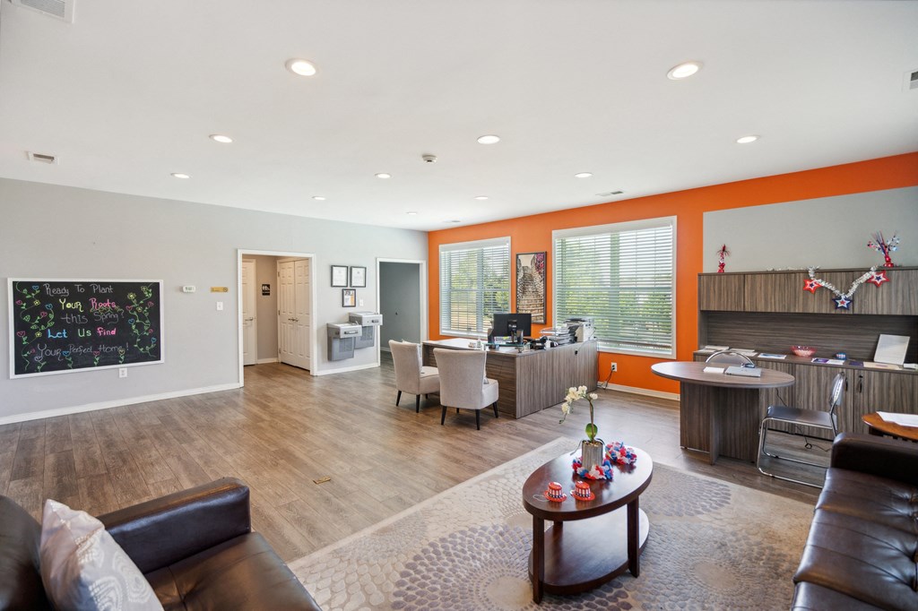 a living room with a couch and a coffee table and a kitchen with a desk