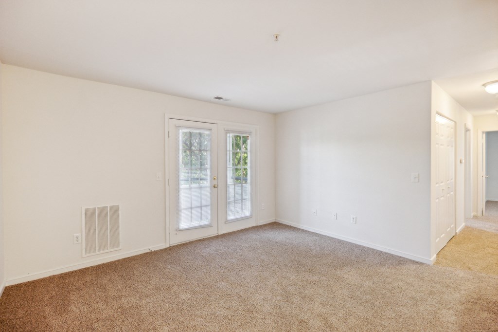 an empty living room with white walls and a door to a hallway