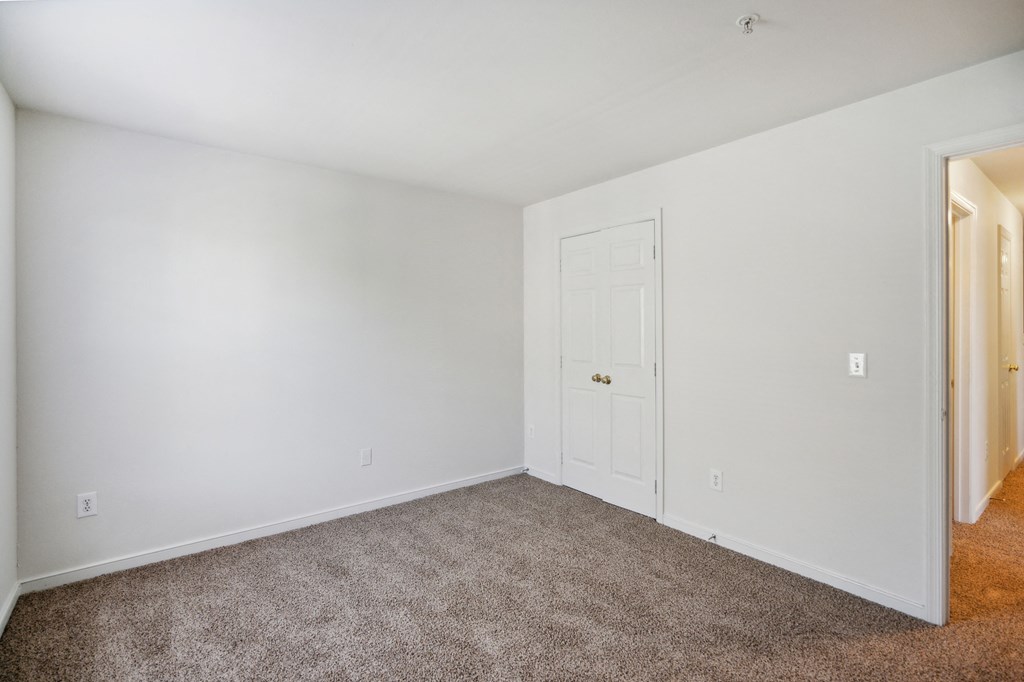 a bedroom with white walls and carpet and a white door