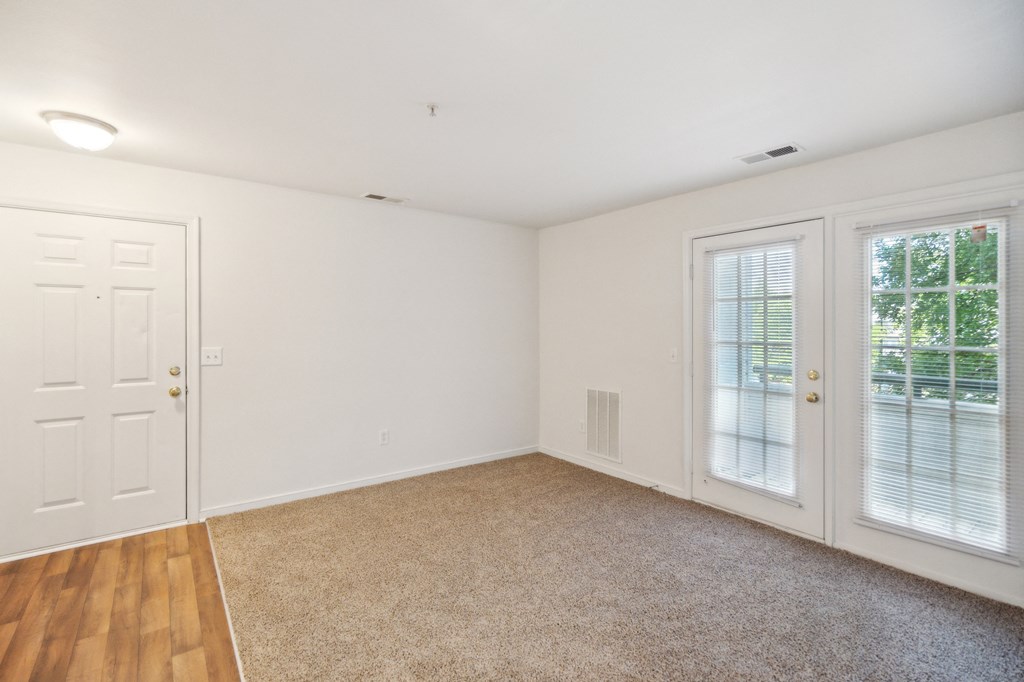 an empty living room with two doors and a window