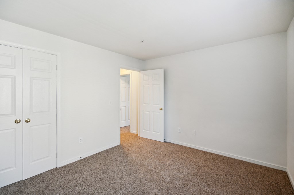 a bedroom with white walls and carpet and white doors