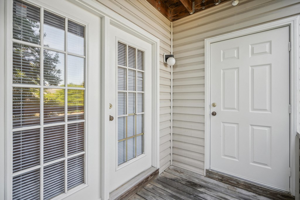 the front porch of a home with a white door and windows