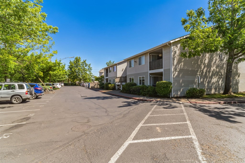 an empty parking lot in front of a building with cars parked in front