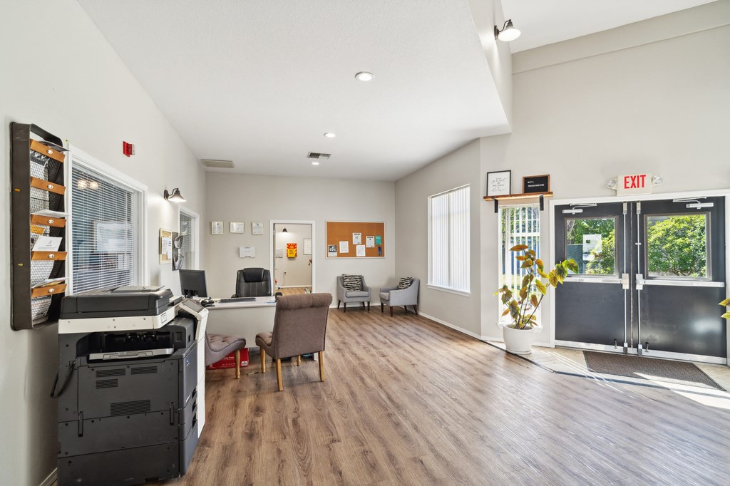 an office space with a desk and a refrigerator and a glass door