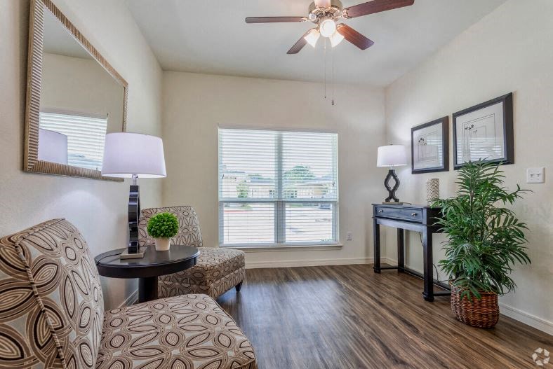 a living room with a chair and a ceiling fan