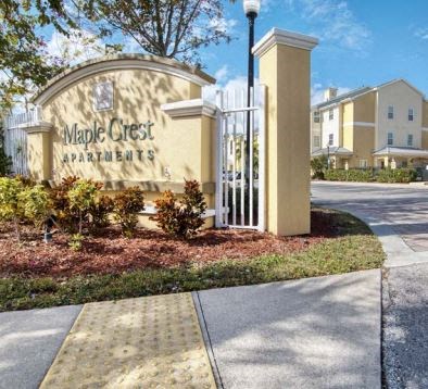 a sign for maple crest apartments in front of a sidewalk