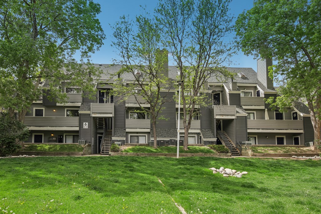 A large grey house with a green lawn in front.