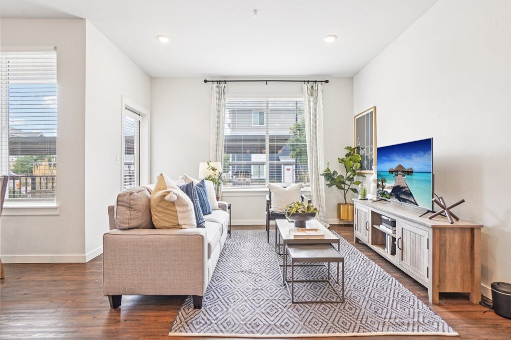 A living room with a couch, a coffee table, and a television. at Connect at First Creek Apartments, Denver, Colorado