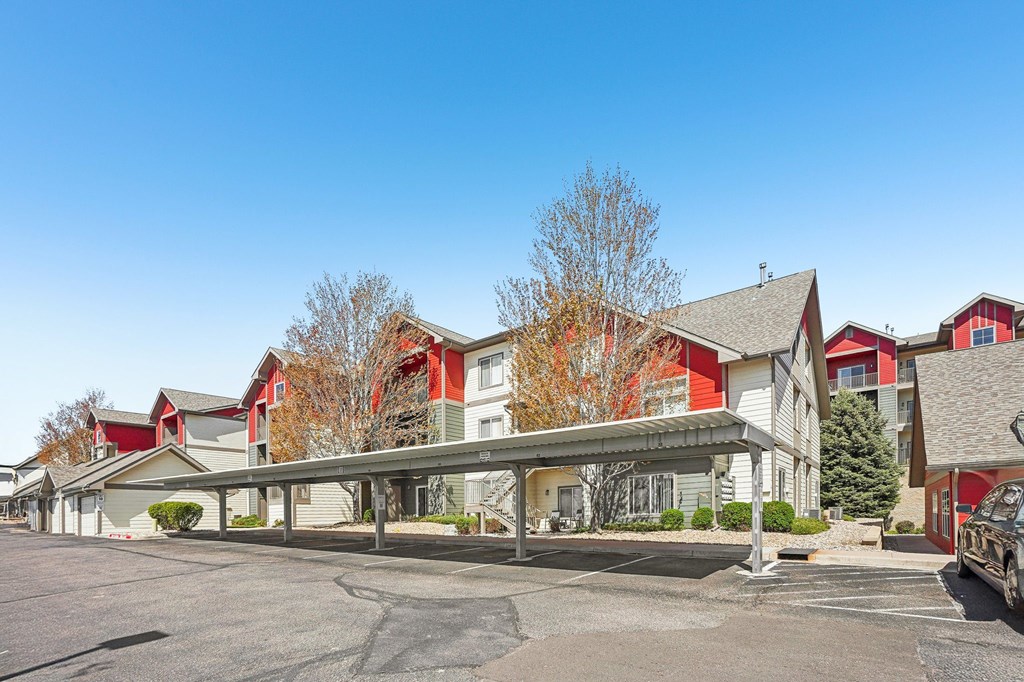 A parking lot in front of a building with a red and white building in the background. at Stetson Meadows Apartments, Colorado Springs, CO, 80922