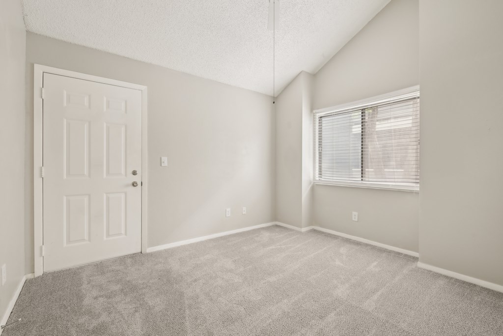 A room with a door and a window with blinds.
