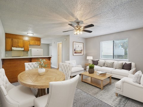A well-lit living room with a dining table and white chairs.