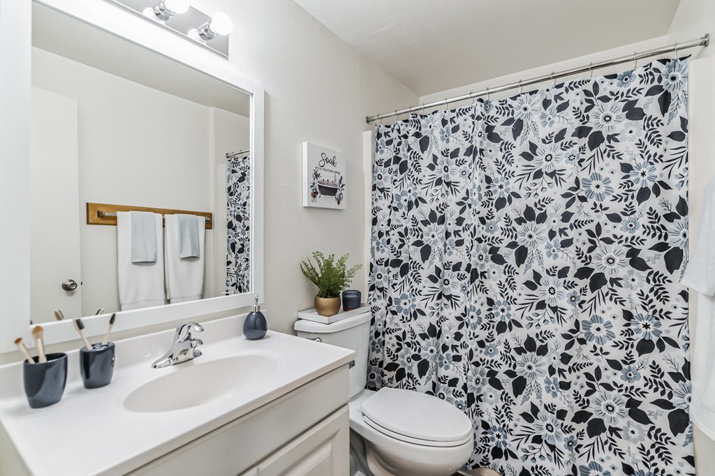 a white bathroom with a black and white shower curtain