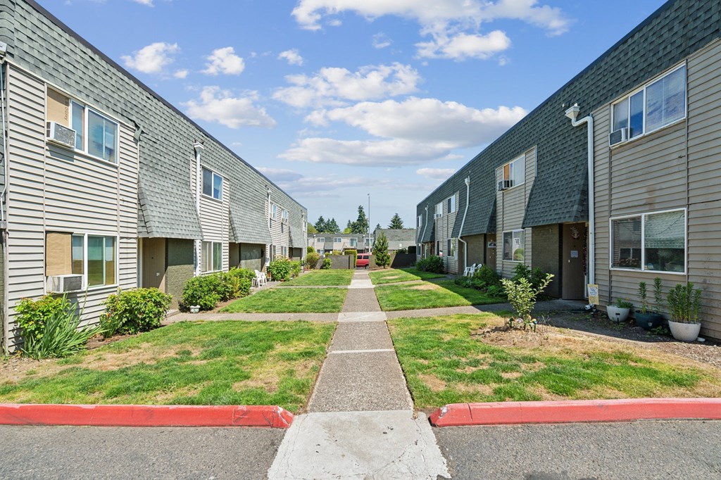 a pathway between two rows of houses with grass
