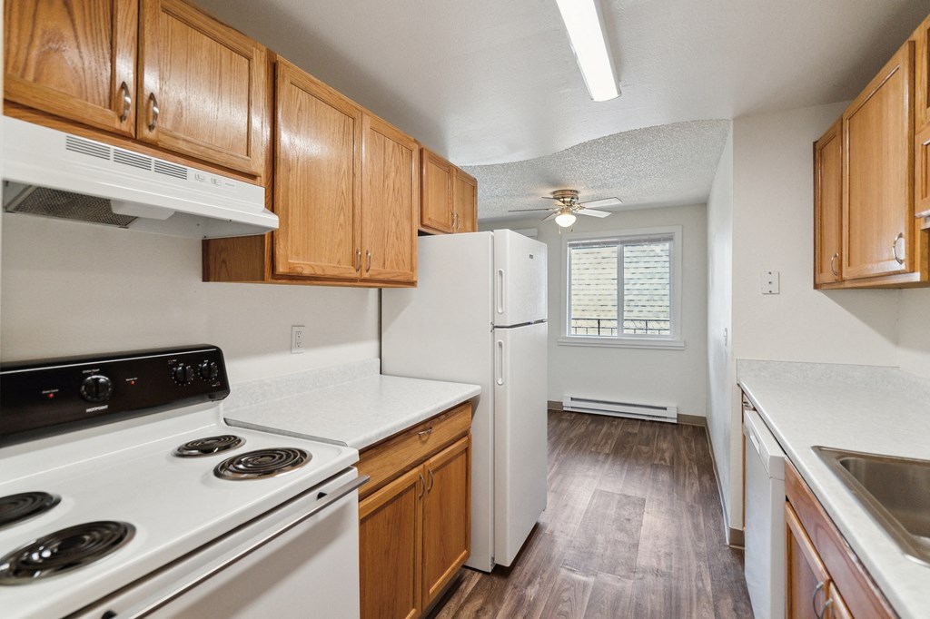 an empty kitchen with white appliances and wooden cabinets