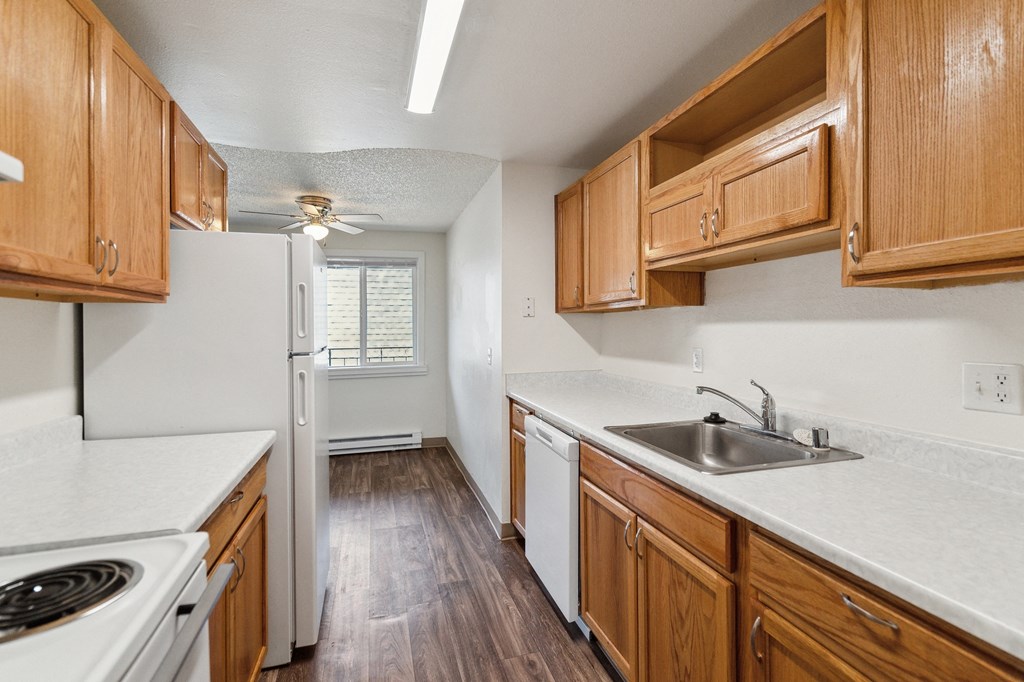 a kitchen with wooden cabinets and white appliances and a sink