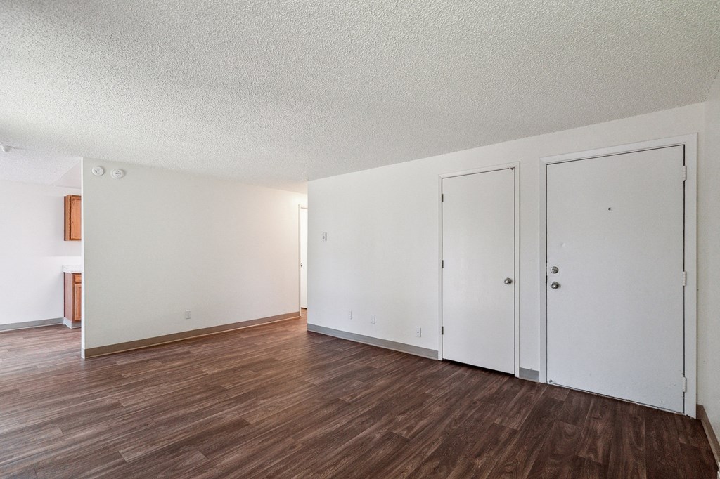 an empty living room with white walls and wood floors