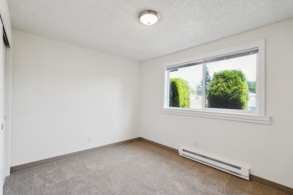 an empty bedroom with a large window and carpeting