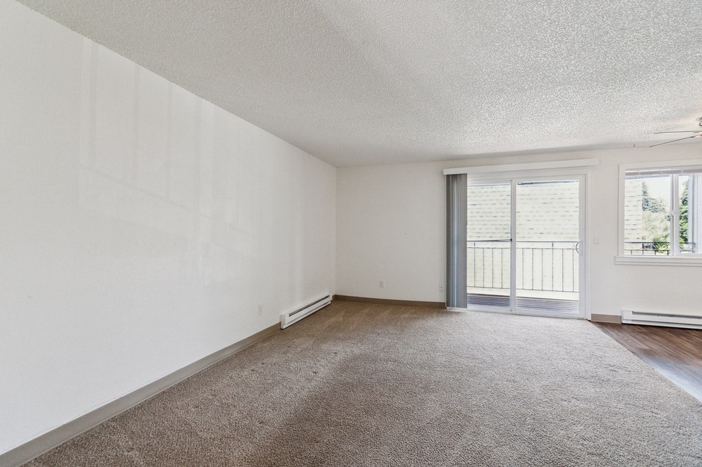an empty living room with a sliding glass door to a balcony