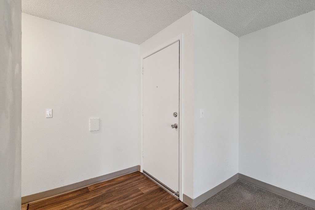 a bedroom with white walls and wood flooring and a white door